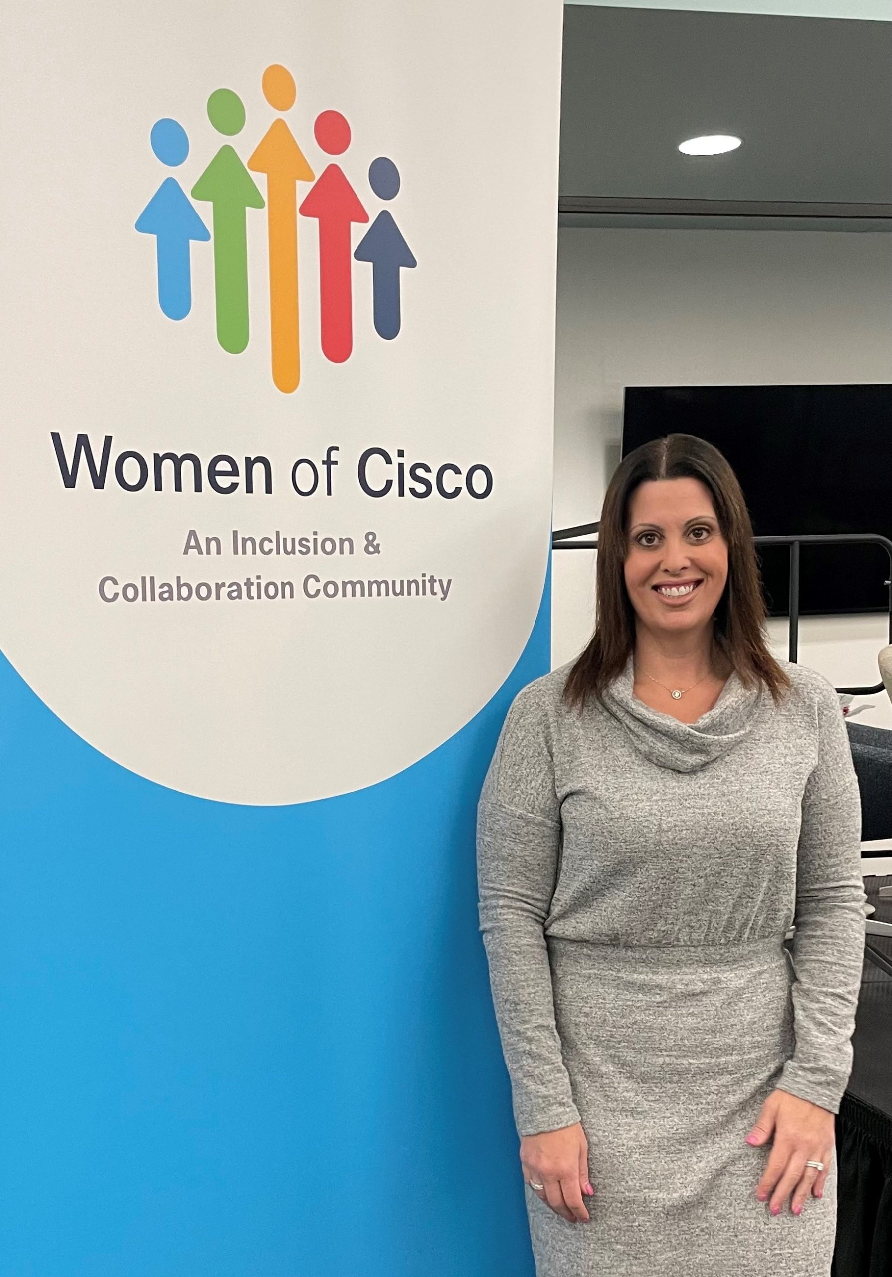 Robyn stands next to a "Women of Cisco" sign.