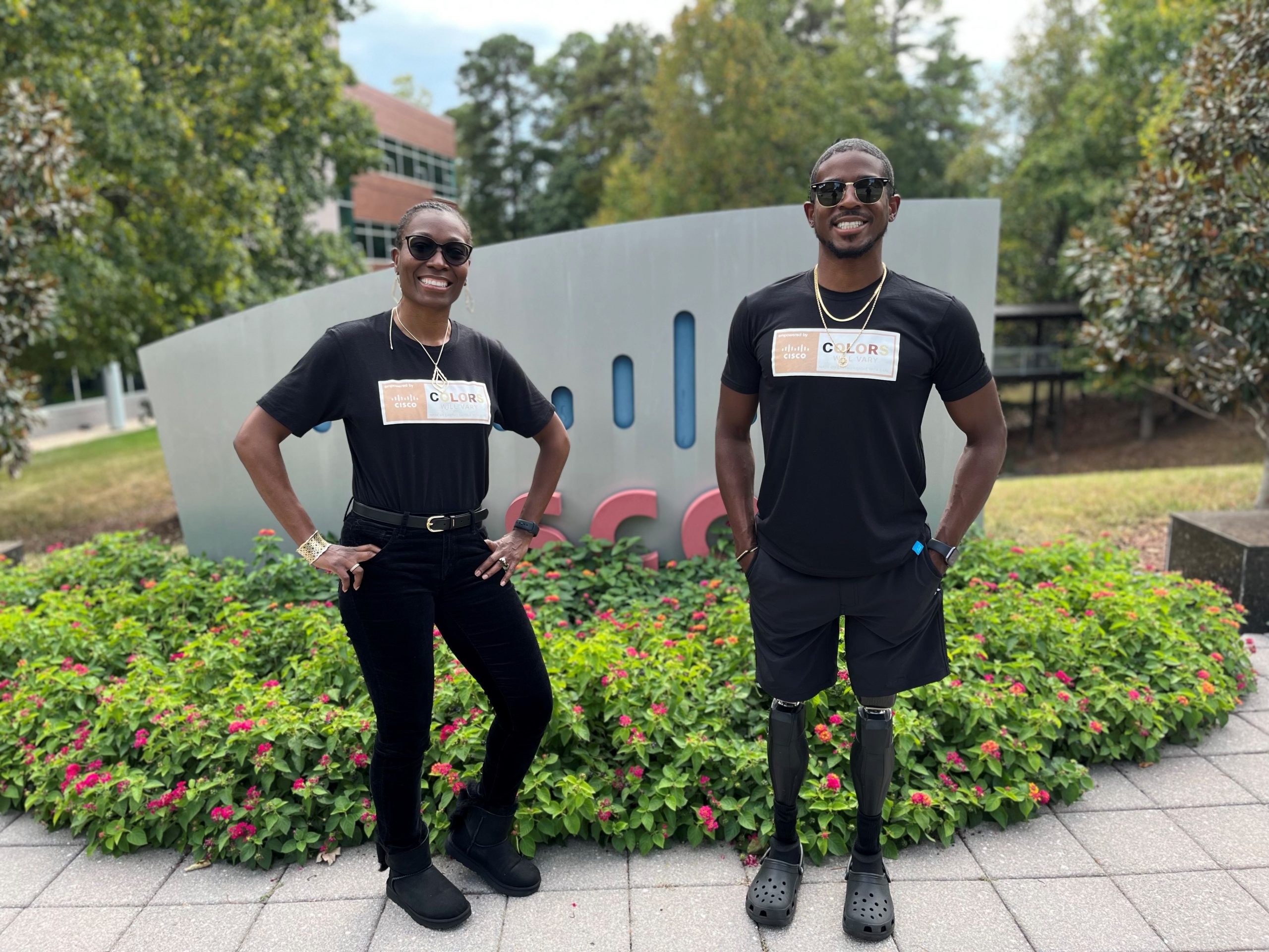 Tracy stands next to her son with a Cisco sign in the background.