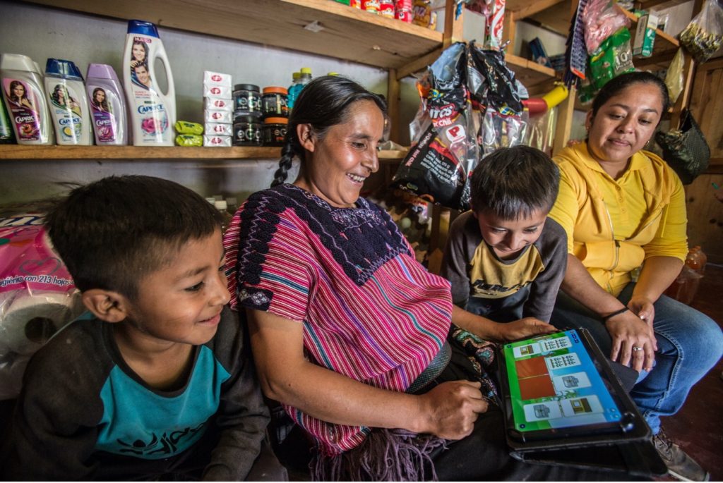 A family gathers around a tablet