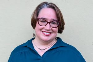 A woman wearing glasses and a blue top