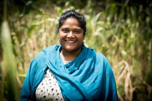 A woman wearing a bright blue scarf in front of a field.