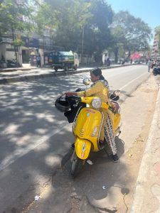 A woman getting on a yellow motorbike.