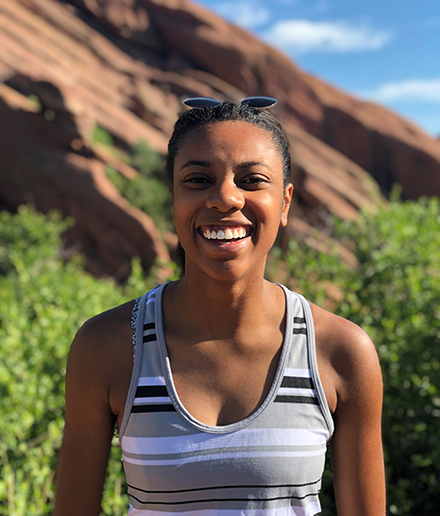 Chrysantha Davis, project specialist for responsible sourcing on Cisco’s Supply Chain Sustainability team, smiling and standing outdoors with a rock formation in the background.
