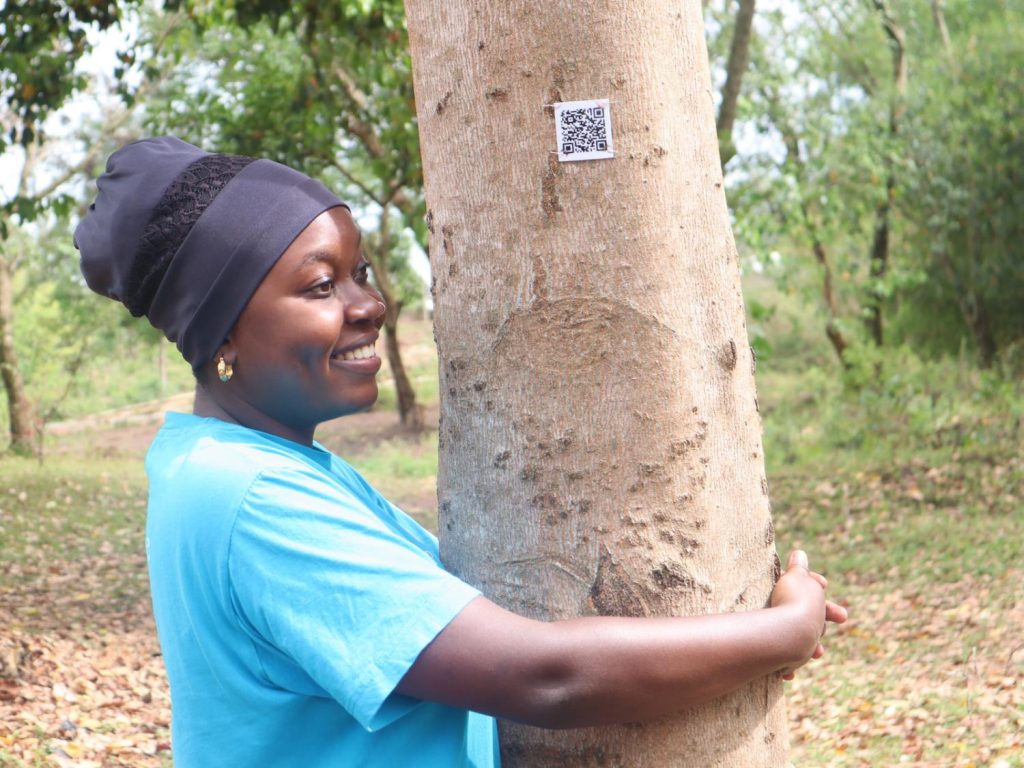 A woman hugging a tree with a QR code on it.