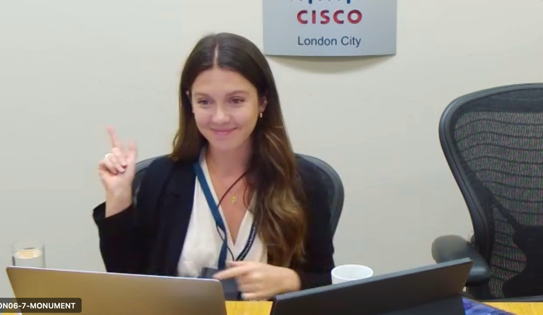 Sandra sitting at desk with laptop and Cisco London City sign in background.