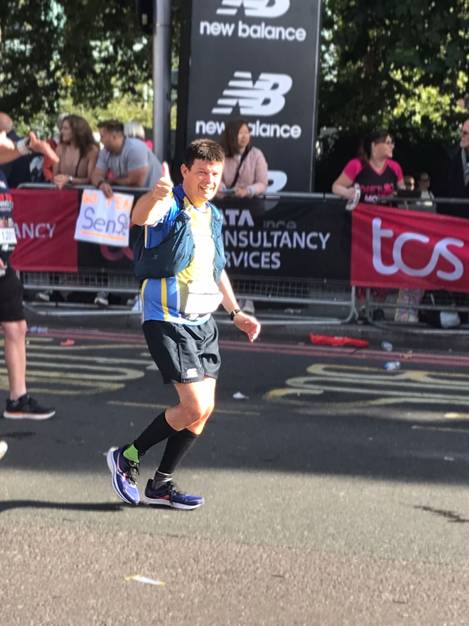 Martin L. running in a marathon while holding a thumbs up gesture. 