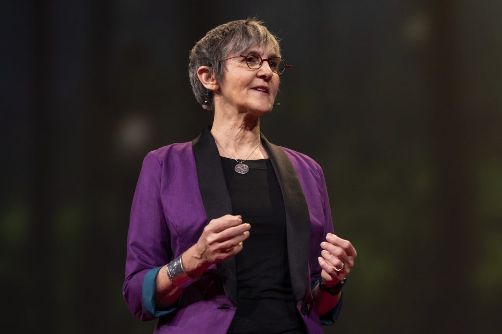 A photo of a woman wearing glasses and a purpose suit.