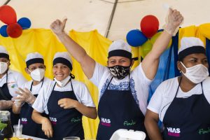 People wearing aprons and face masks, one of them with raised arms