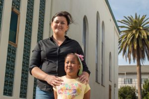 A mother with her daughter standing outside a building