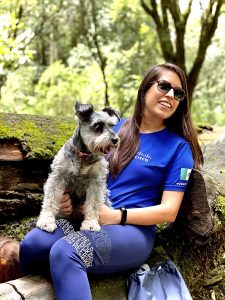 Woman in blue Cisco shirt holding gray dog on her lap.