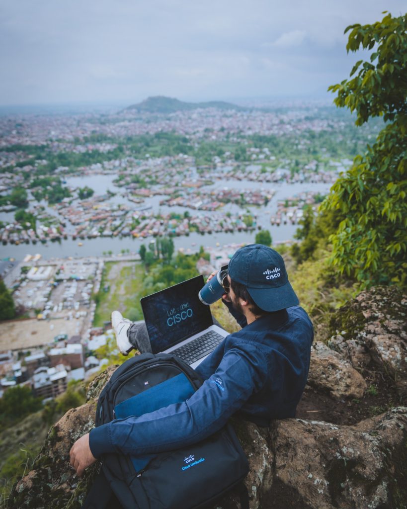Haroon sitting on rocks sipping out of Cisco mug overlooking city and canals.