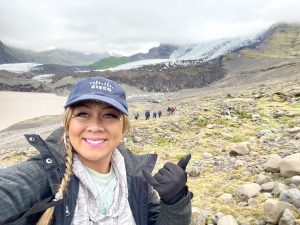 Woman wearing navy blue Cisco hat with mountains and fog behind her.