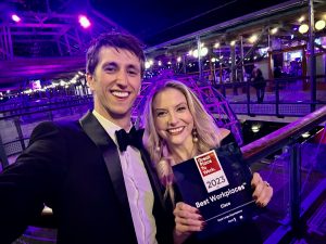 Two people dressed in black-tie holding Great Place to Work Best Workplace award.