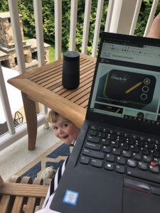 Child peeking out from under table while parent is on Cisco check-in on laptop.