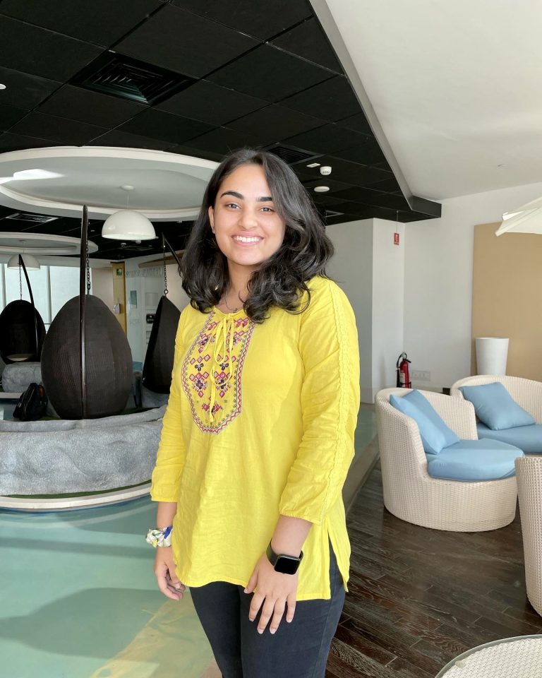Sanya smiling and wearing a yellow shirt.