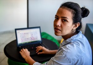 Woman on laptop looking over shoulder at camera