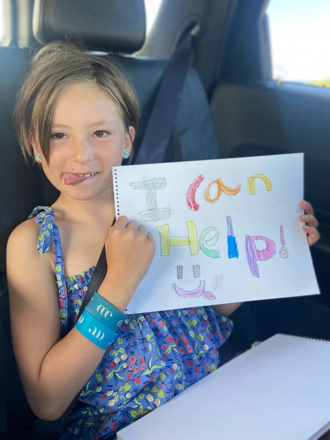 Rick's daughter holding up a sign that reads, "I can help."