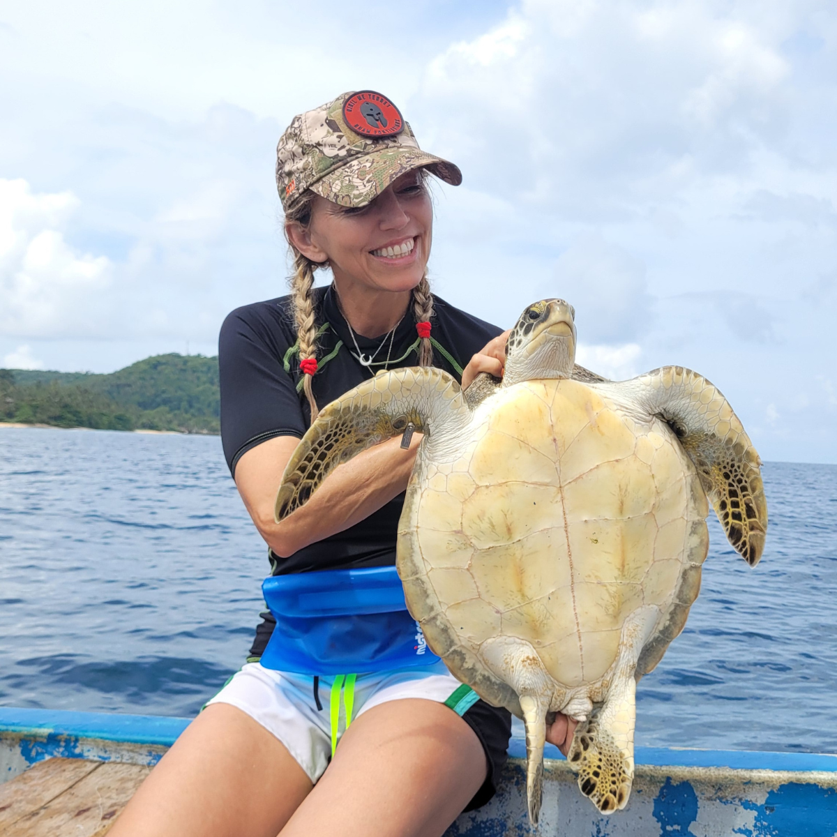 Cristina holding a sea turtle on a boat.