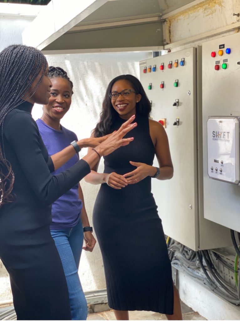 A woman in a black dress standing next to renewable energy equipment.