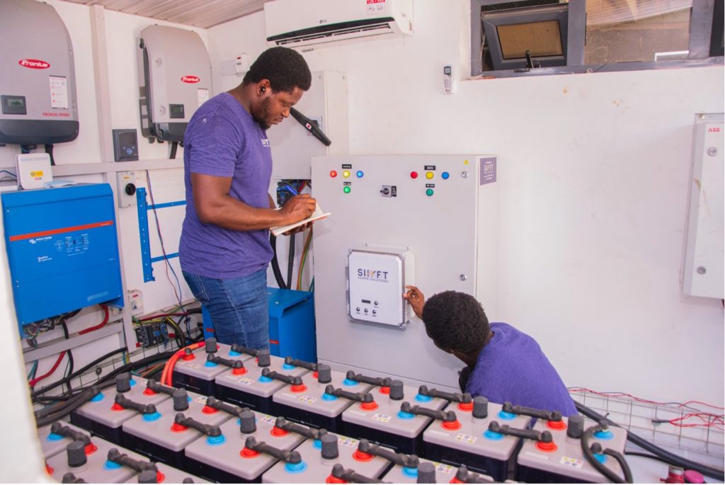 Two men in purple shirts installing renewable energy.