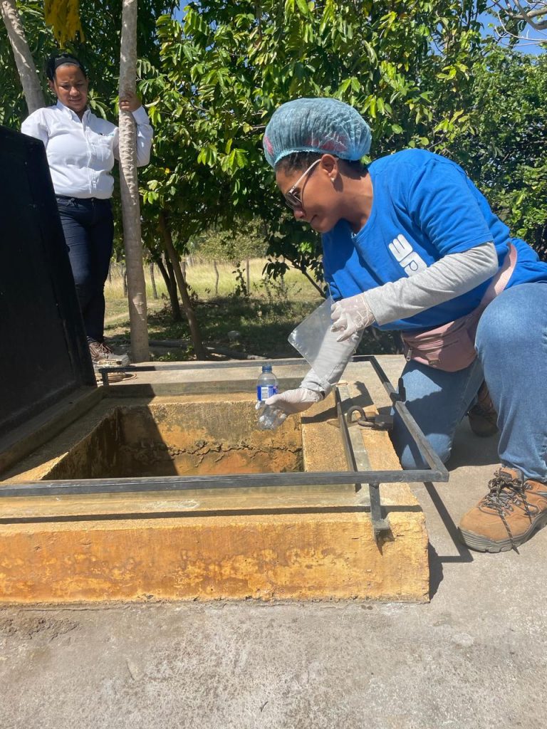 A woman working on a water project wearing a blue shirt