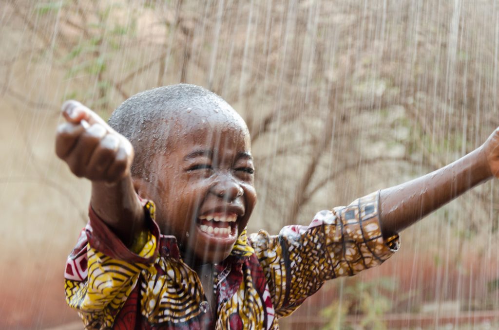 A child with outstretched hands with drops of water falling