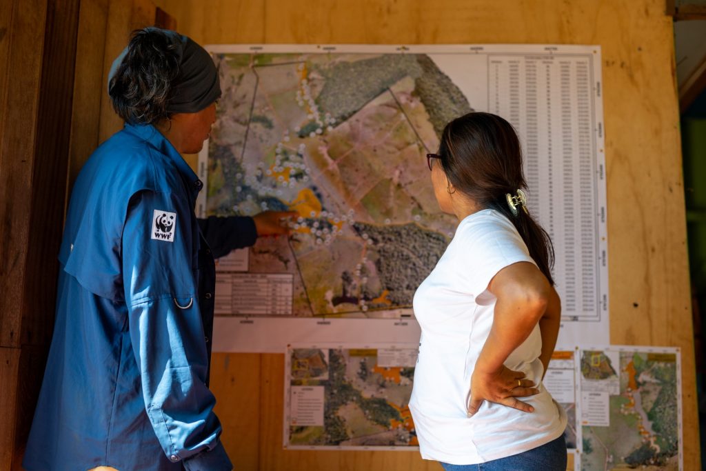 Two people standing in a room, looking at a map on the wall together.