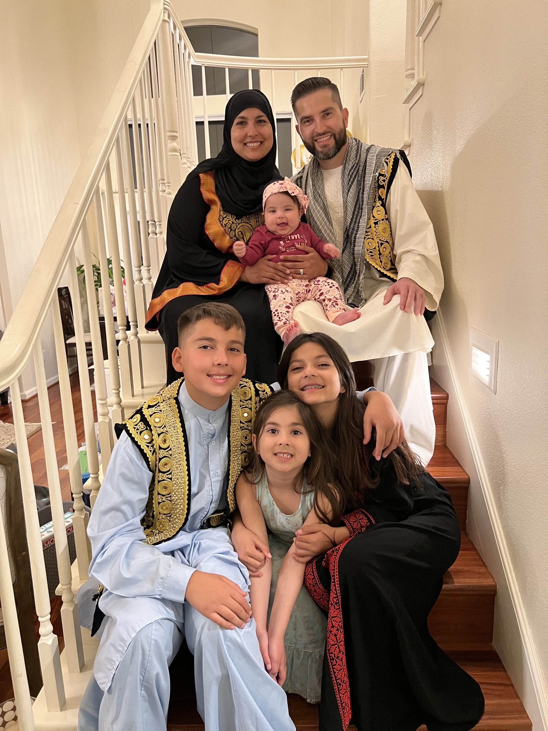 Wallid and family dressed up sitting on stairs posing for photo