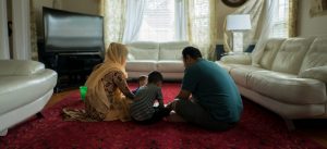 Family sits on floor together in living room 