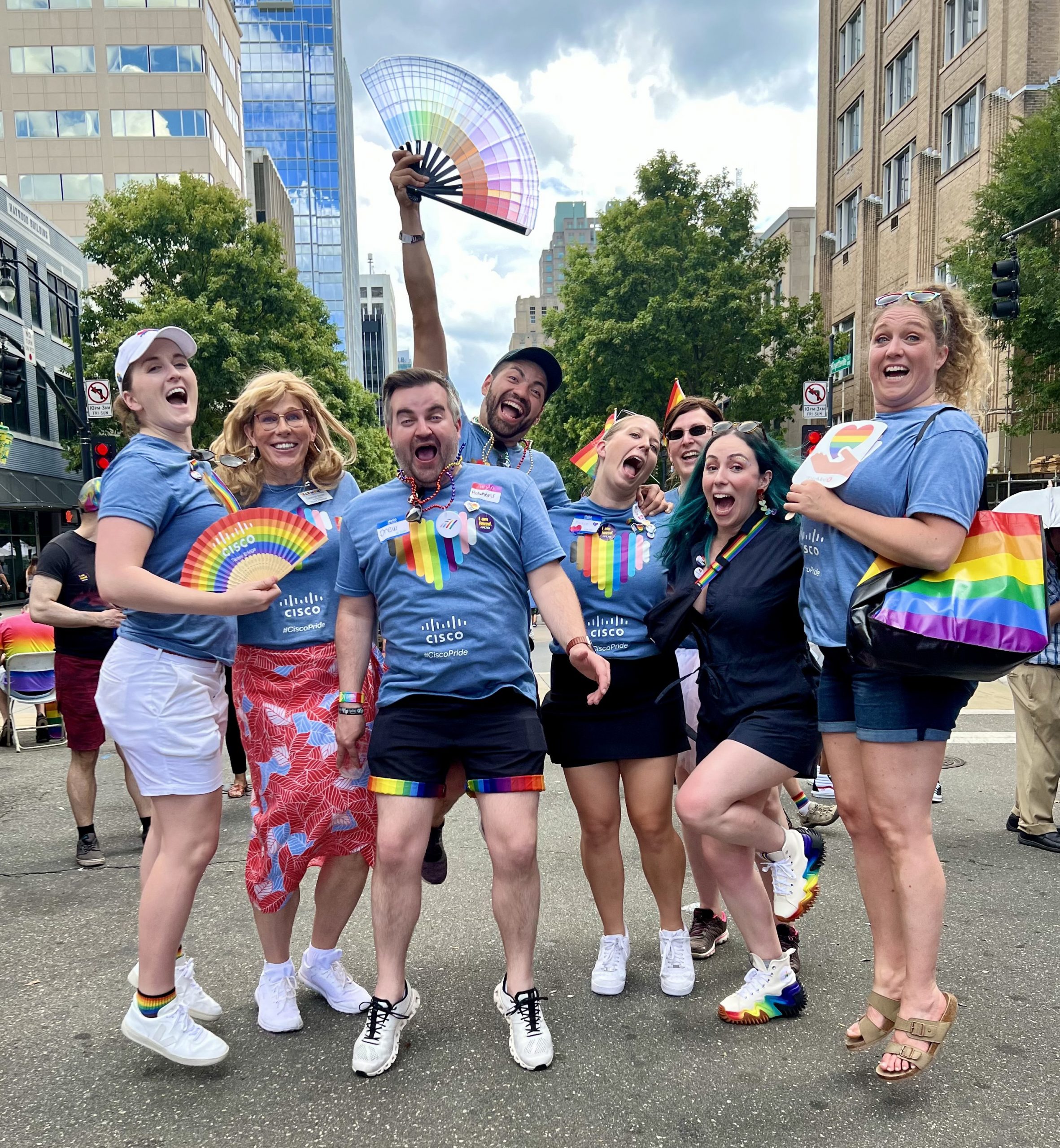 Group shot of pride members and allies wearing blue Cisco pride tshirts jumping in the air.