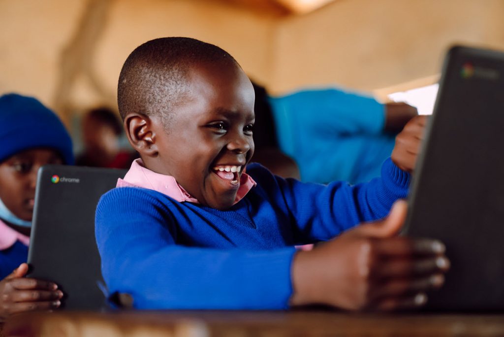 2Young child smiles as he learns how to code on a digital screen.