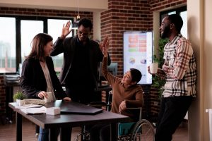 Four people high fiving around a table in an office