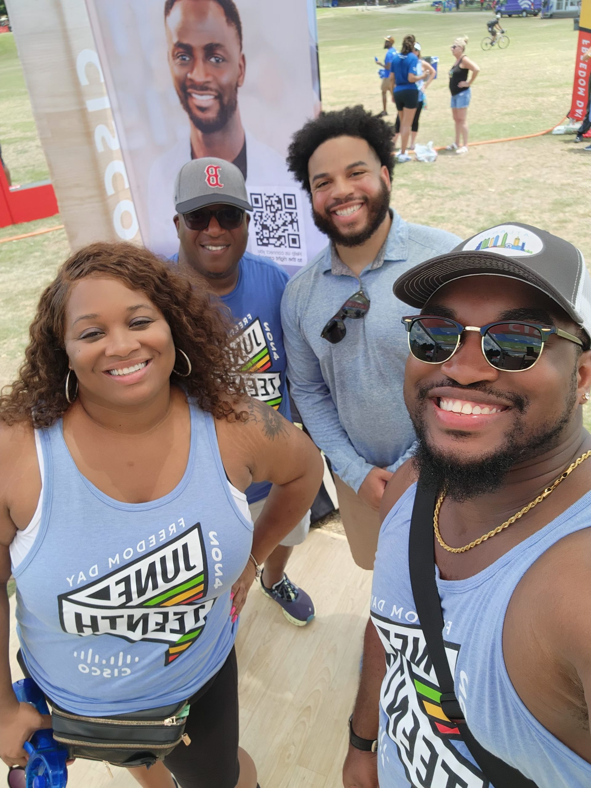 Four Cisco employees, three wearing blue Juneteenth shirts, pose for a selfie. 