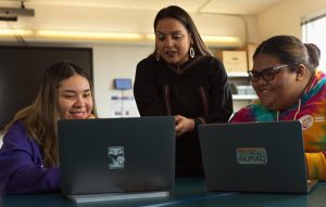 Justina Wilhelm, president of Iḷisaġvik College, speaking with students who are looking at their laptops.