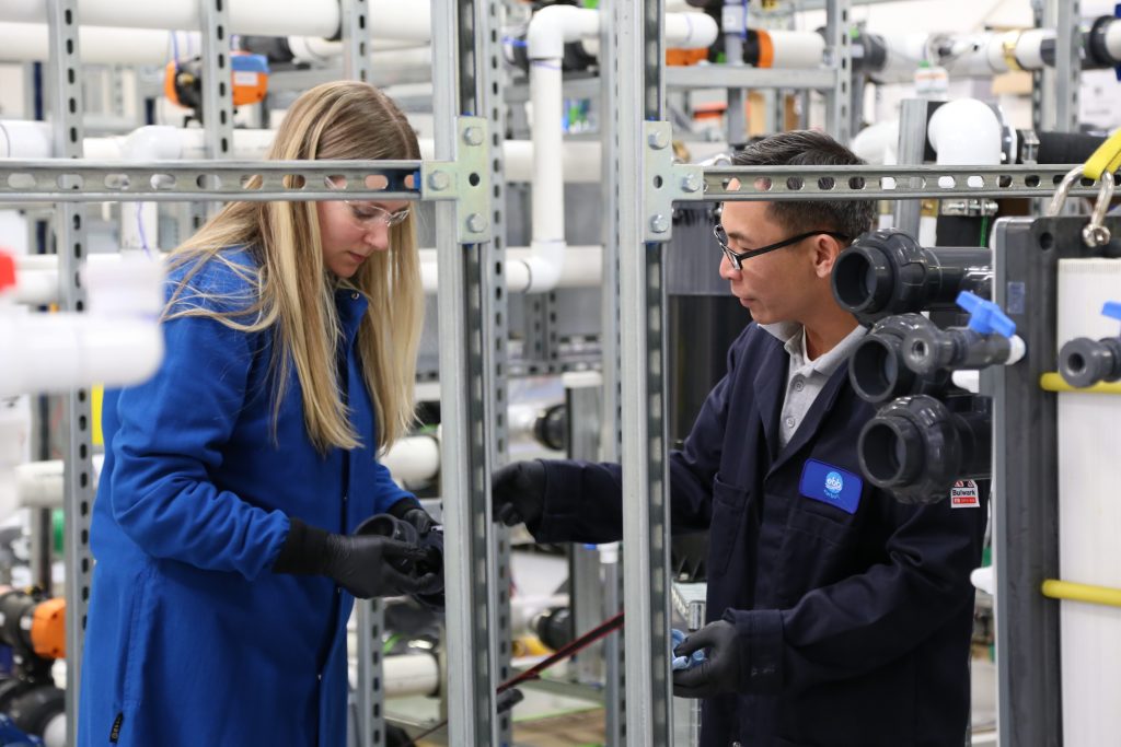 Two people in lab uniforms in a lab setting