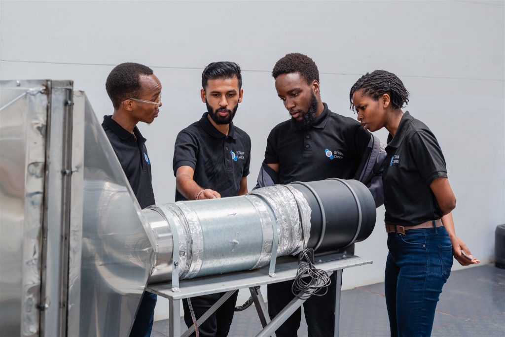 A group of people in black shirts inspecting a piece of tech equipment