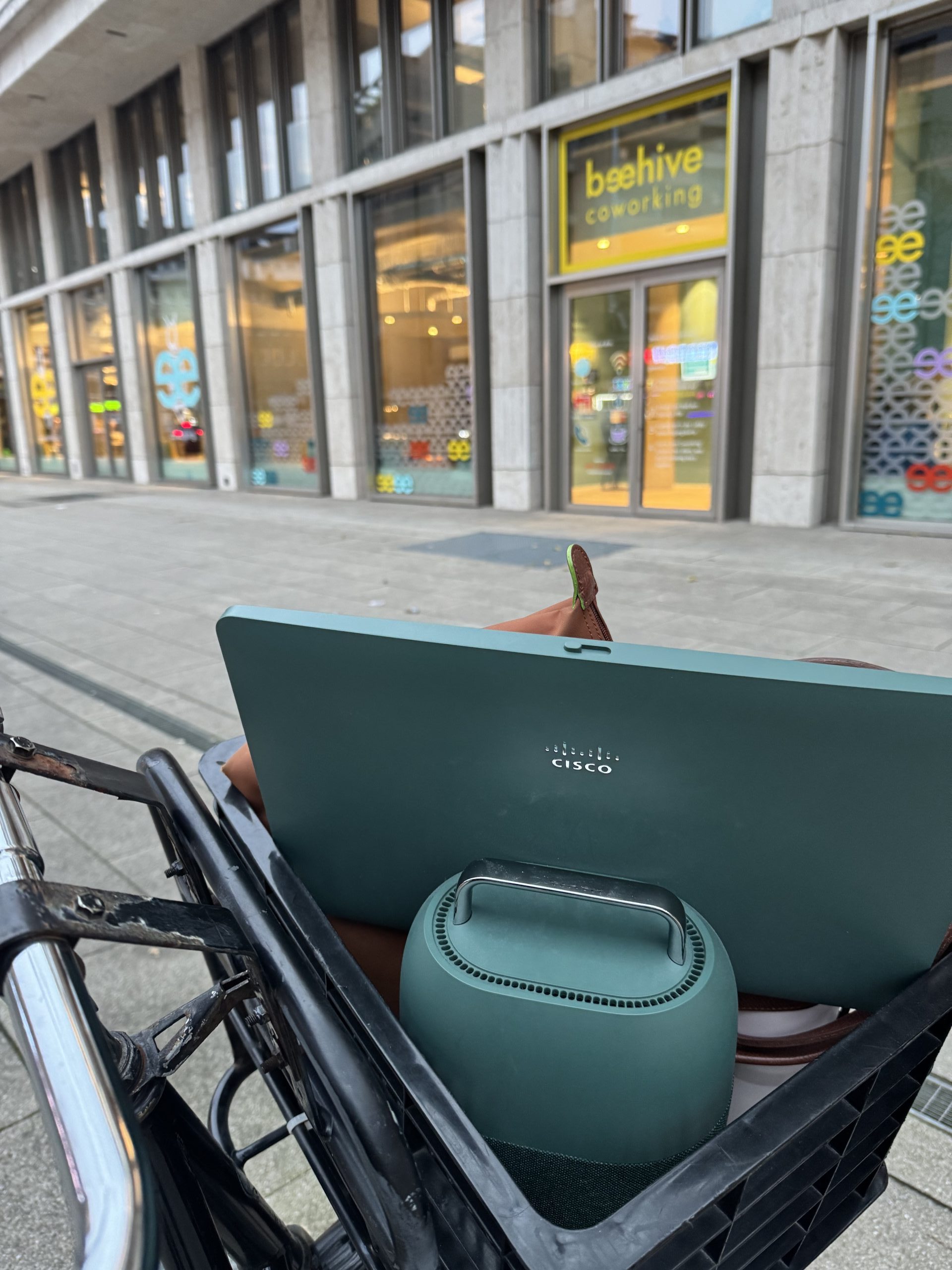 Front of a bicycle with a basket with Cisco desktop mini inside.