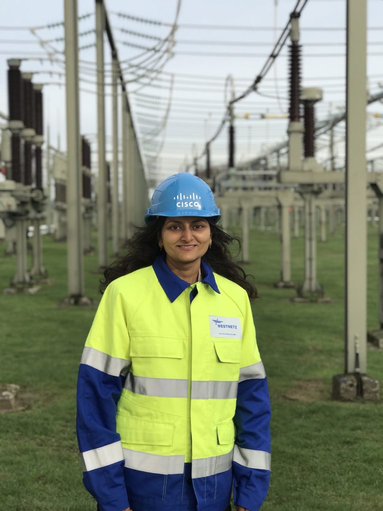 A woman wearing a helmet with "Cisco" on it, visiting a substation