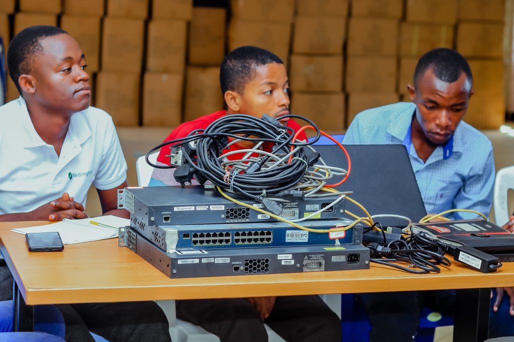 Group of 3 students with technology in the front.