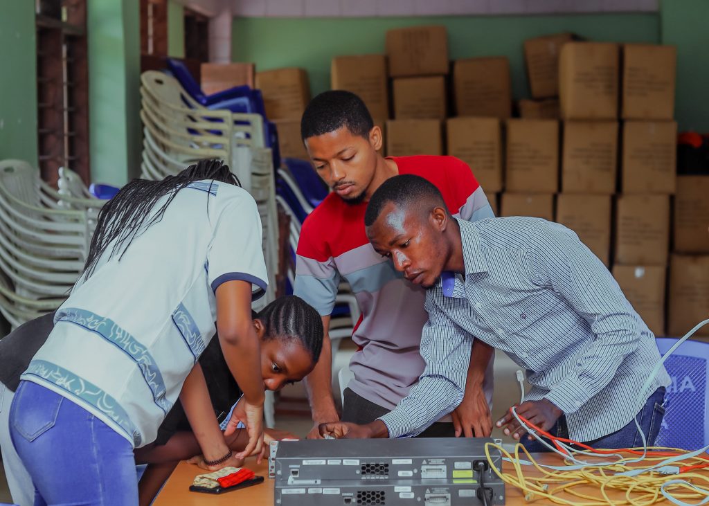 A group of four students are around a computer device.