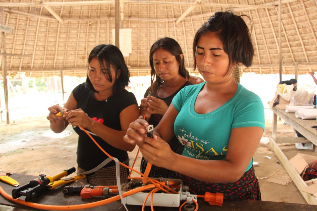Three women working on solar power boat equipment