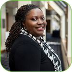 A woman wearing a black suit with a black and white scarf