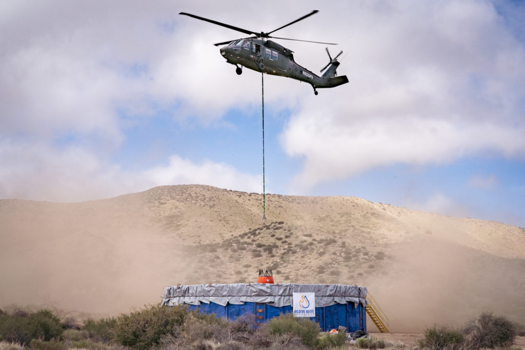 A helicopter collecting water in a desert landscape.