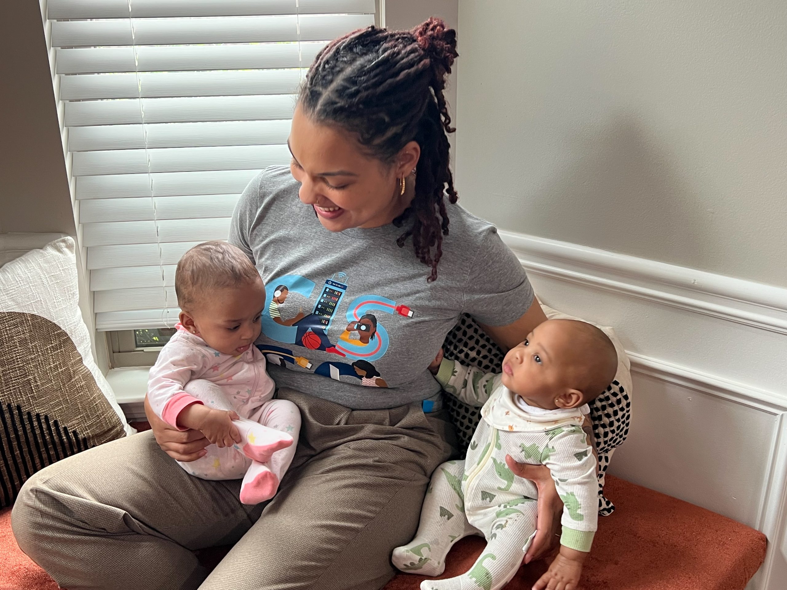 Mom holding one baby on her lap and the other beside her.
