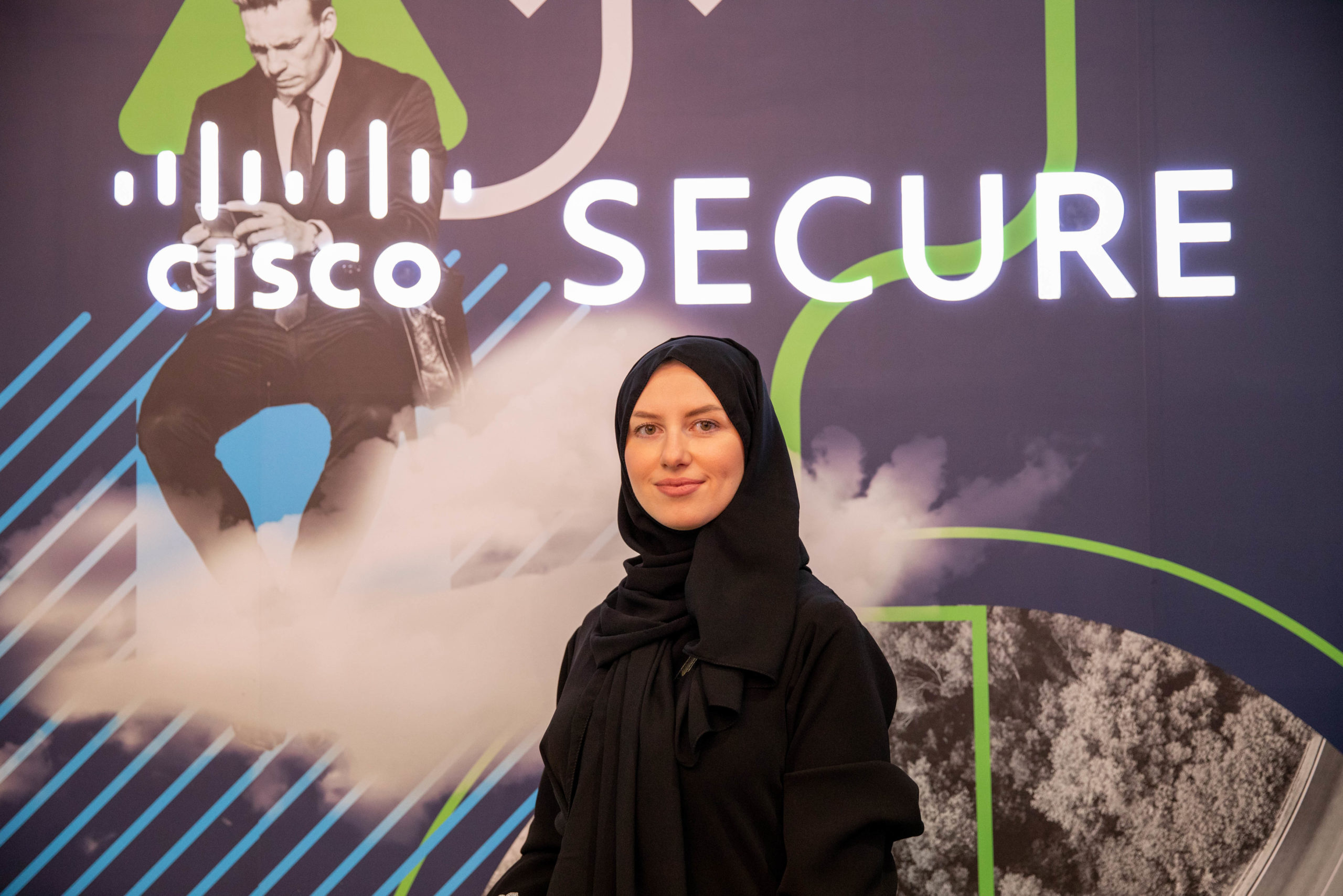 Women in black headscarves standing in front of a Cisco Secure backdrop.