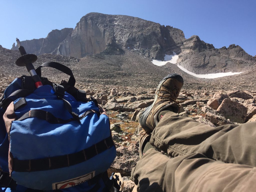 A blue backpack and boots with a mountain in the background.