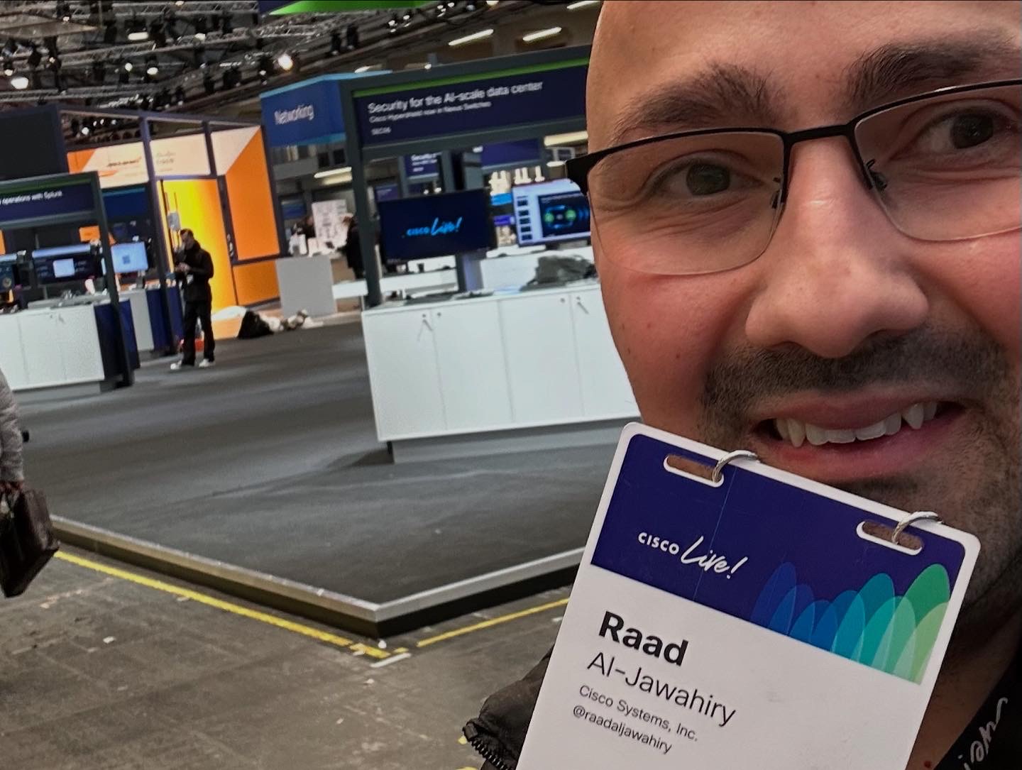 A man holding his Cisco Live badge smiles.