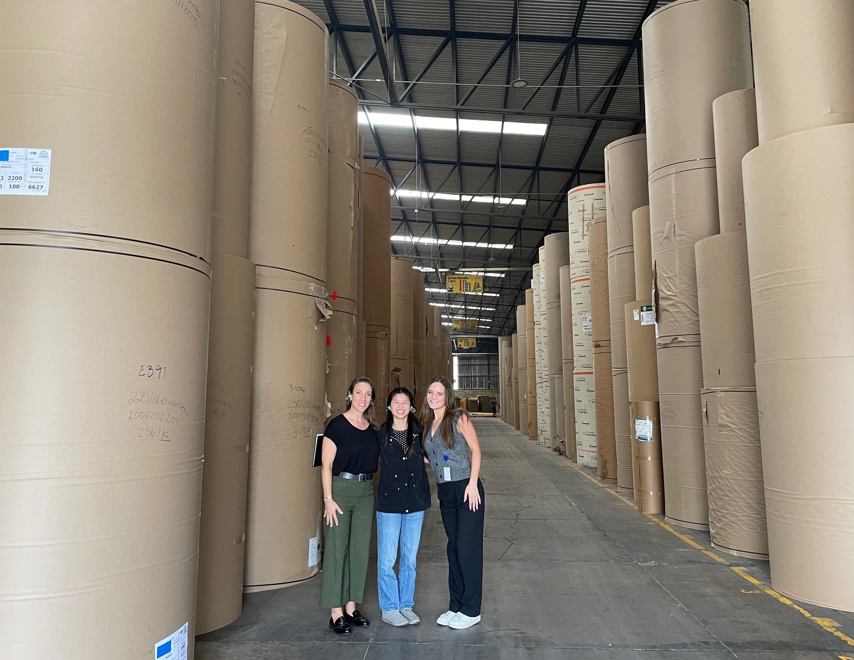 Three women standing in a factory setting.