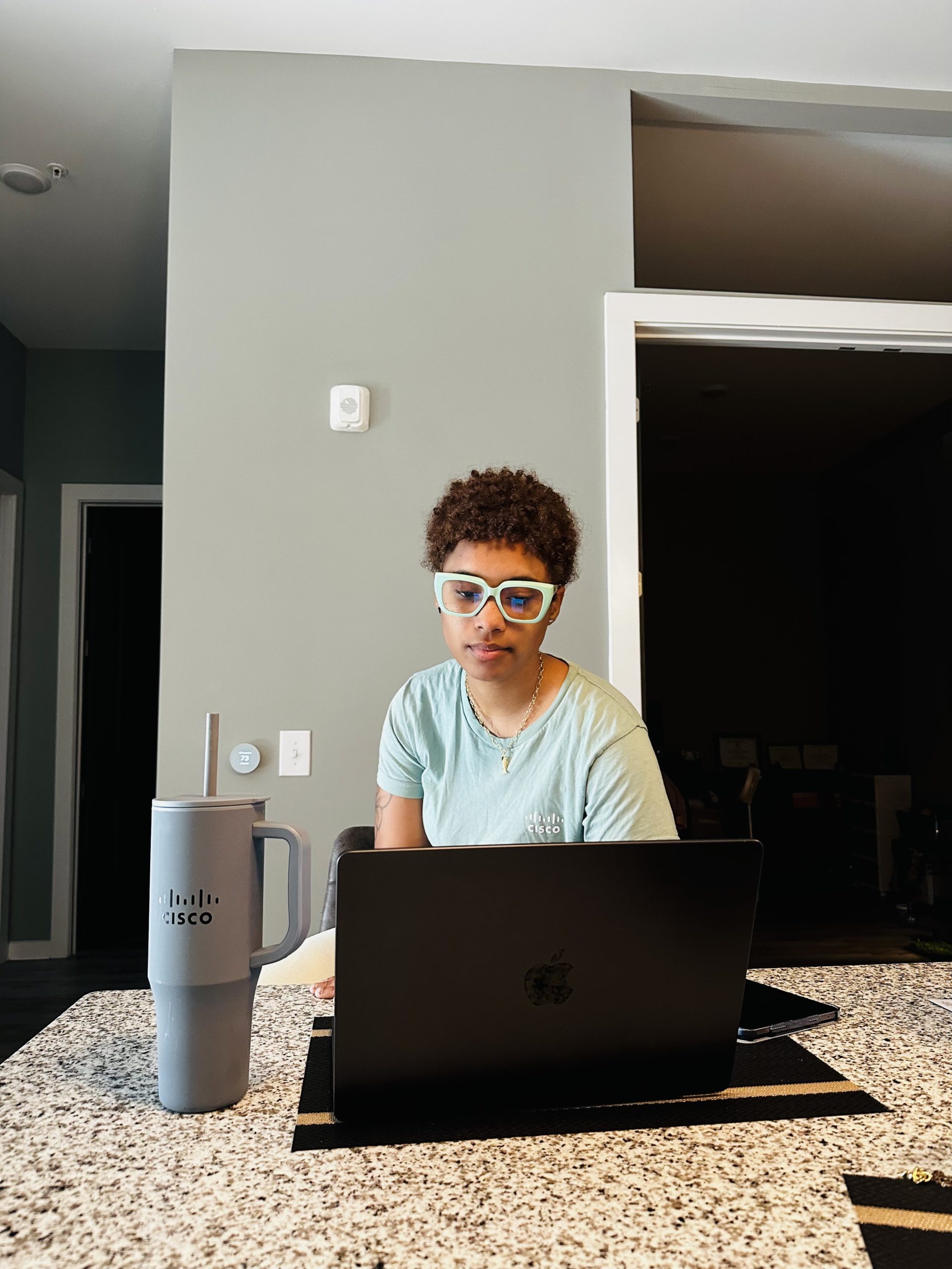 Women sitting at countertop with laptop and Cisco branded water bottle.