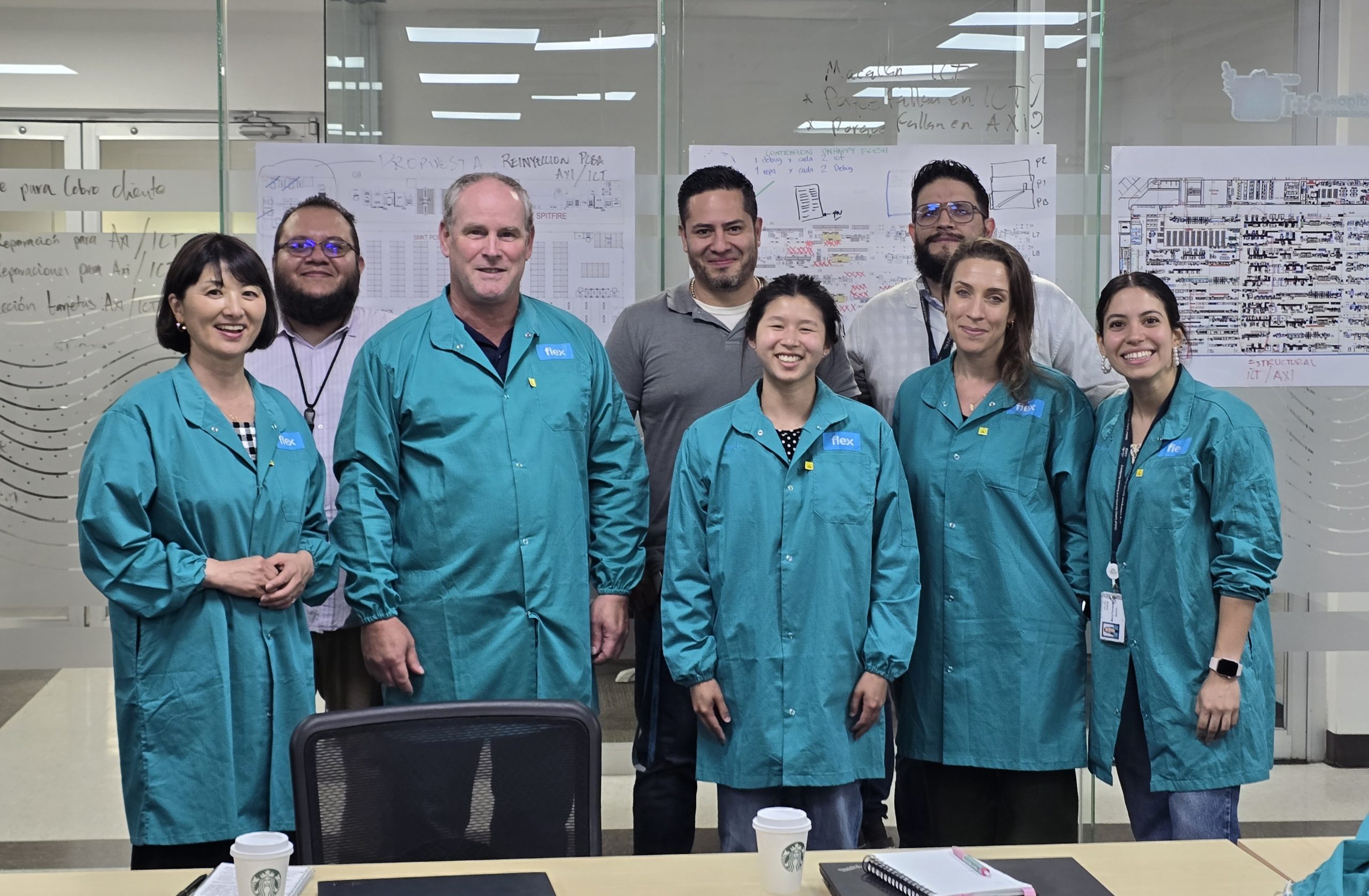 A group of people, wearing blue lab coats, in a supply chain setting.